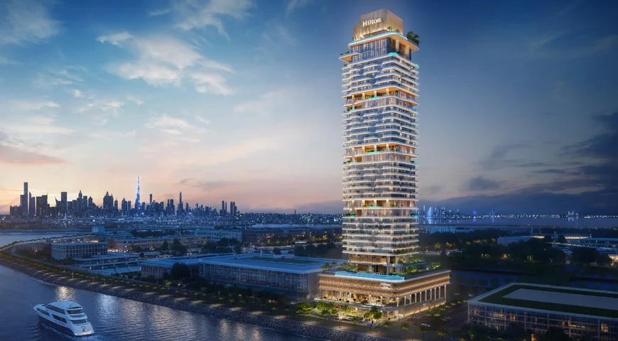 Hilton Residences rising above the waterfront at Dubai Maritime City at dusk, with the Downtown skyline beyond